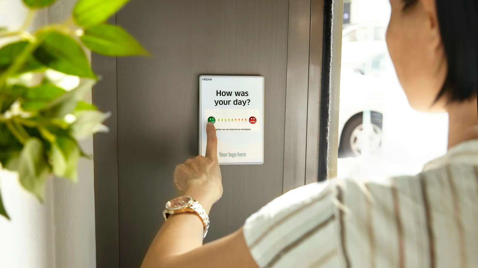 A person gives feedback using a simple smiley-button survey terminal.